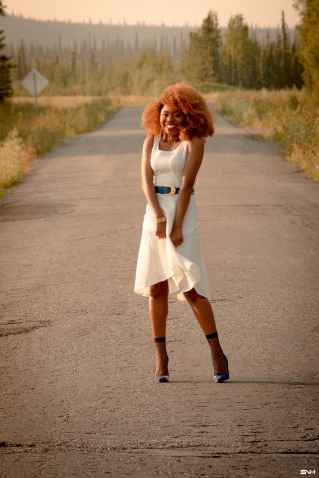 Can't get over her stunning white summer dress! ? Twirling in the prairie fields. Her sleeveless A-line midi dress has the perfect flare. Bold statement hoop earrings and embellished blue belt perfects her outfit. A dress that you can dress up or down! Little white dress, flare dress, Dress with flare, White dress, Summer dress, Formal dress, Modest dress, Wedding guest outfit, Black girl, Classy dress, womens style