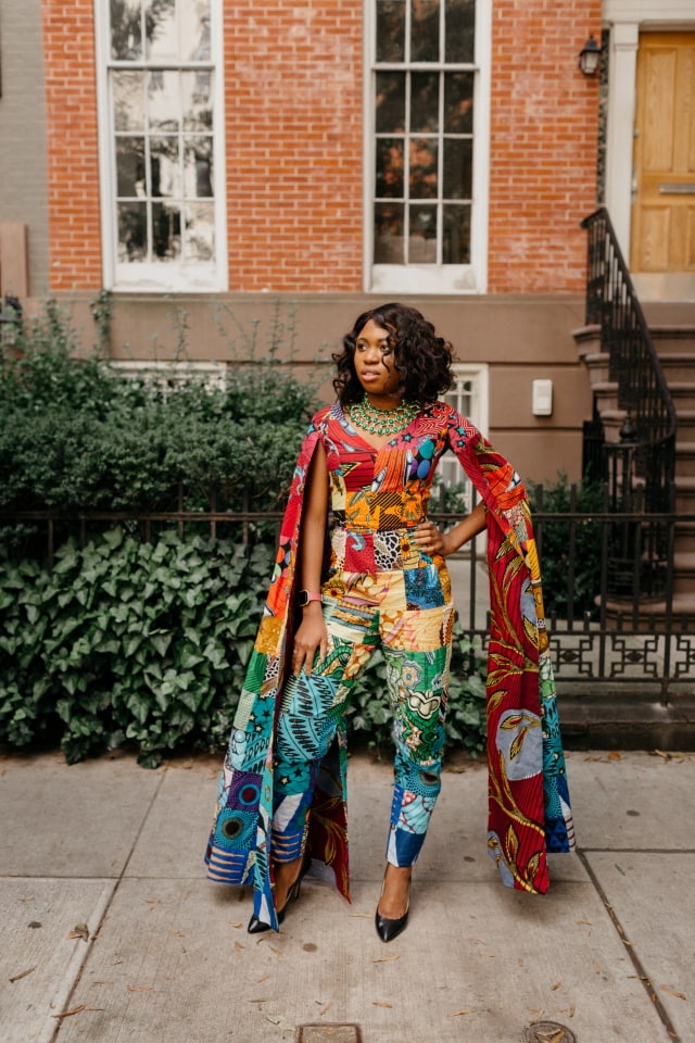 How I love the dramatic cape sleeves of this rainbow patchwork ankara jumpsuit. I'm sure she turned heads when she showed up to New York Fashion Week dressed like this. With simple wavy hair, black pumps and green statement necklace to match, it'll be no surprise if the media swoons over her. Stunning NYFW Fall/Winter 2017 outfit #NYFW #NewYorkFashionWeek #Ankara #Kente