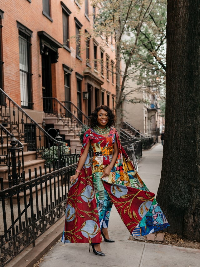 How I love the dramatic cape sleeves of this rainbow patchwork ankara jumpsuit. I'm sure she turned heads when she showed up to New York Fashion Week dressed like this. With simple wavy hair, black pumps and green statement necklace to match, it'll be no surprise if the media swoons over her. Stunning NYFW Fall/Winter 2017 outfit #NYFW #NewYorkFashionWeek #Ankara #Kente