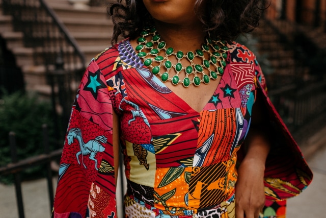 How I love the dramatic cape sleeves of this rainbow patchwork ankara jumpsuit. I'm sure she turned heads when she showed up to New York Fashion Week dressed like this. With simple wavy hair, black pumps and green statement necklace to match, it'll be no surprise if the media swoons over her. Stunning NYFW Fall/Winter 2017 outfit #NYFW #NewYorkFashionWeek #Ankara #Kente