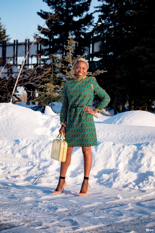 African style blogger, Louisa showcases stylish African print clothes in an epic 30-day series. Day 21 knocks our socks off in a breathtaking belted ankara office dress by Maggie Gold. This conservative office wear shows how versatile African attires are for everyday looks. She finishes off the look with a structured luggage purse, patent classic heels, and trendy lace ankle socks. Check it out! #ankara #dashiki #kente