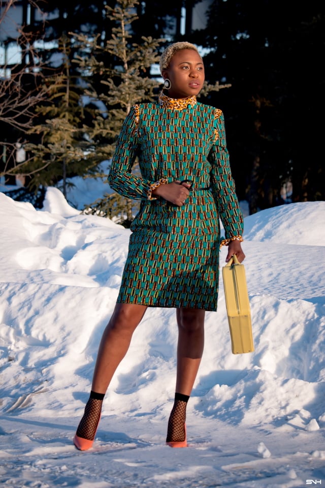 African style blogger, Louisa showcases stylish African print clothes in an epic 30-day series. Day 21 knocks our socks off in a breathtaking belted ankara office dress by Maggie Gold. This conservative office wear shows how versatile African attires are for everyday looks. She finishes off the look with a structured luggage purse, patent classic heels, and trendy lace ankle socks. Check it out! #ankara #dashiki #kente