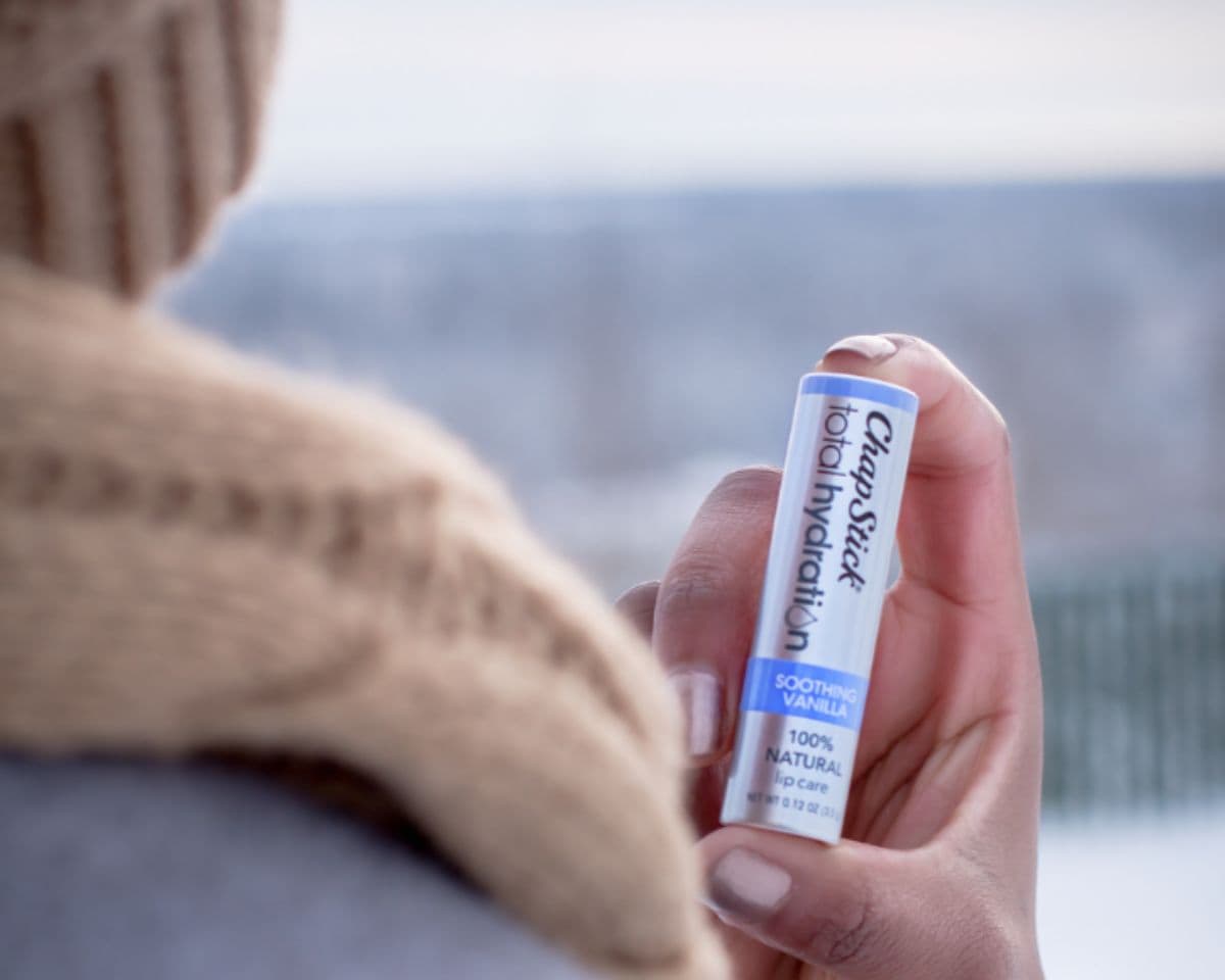 holding lip balm in hand in winter outside 