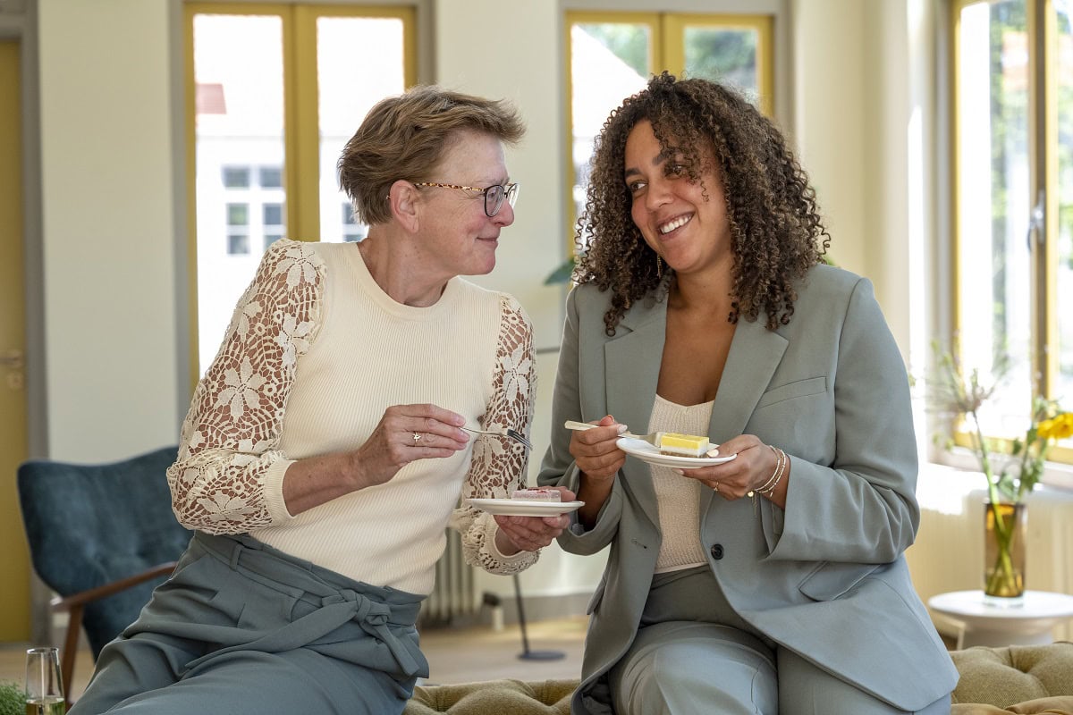 two women enjoying cake together in a well lit roo 2024 08 19 21 54 35 utc