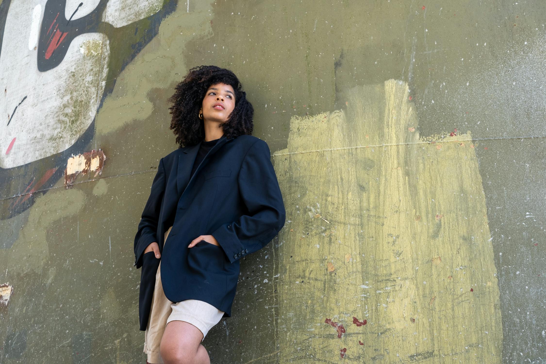 free photo of woman wearing blazer in front of graffiti