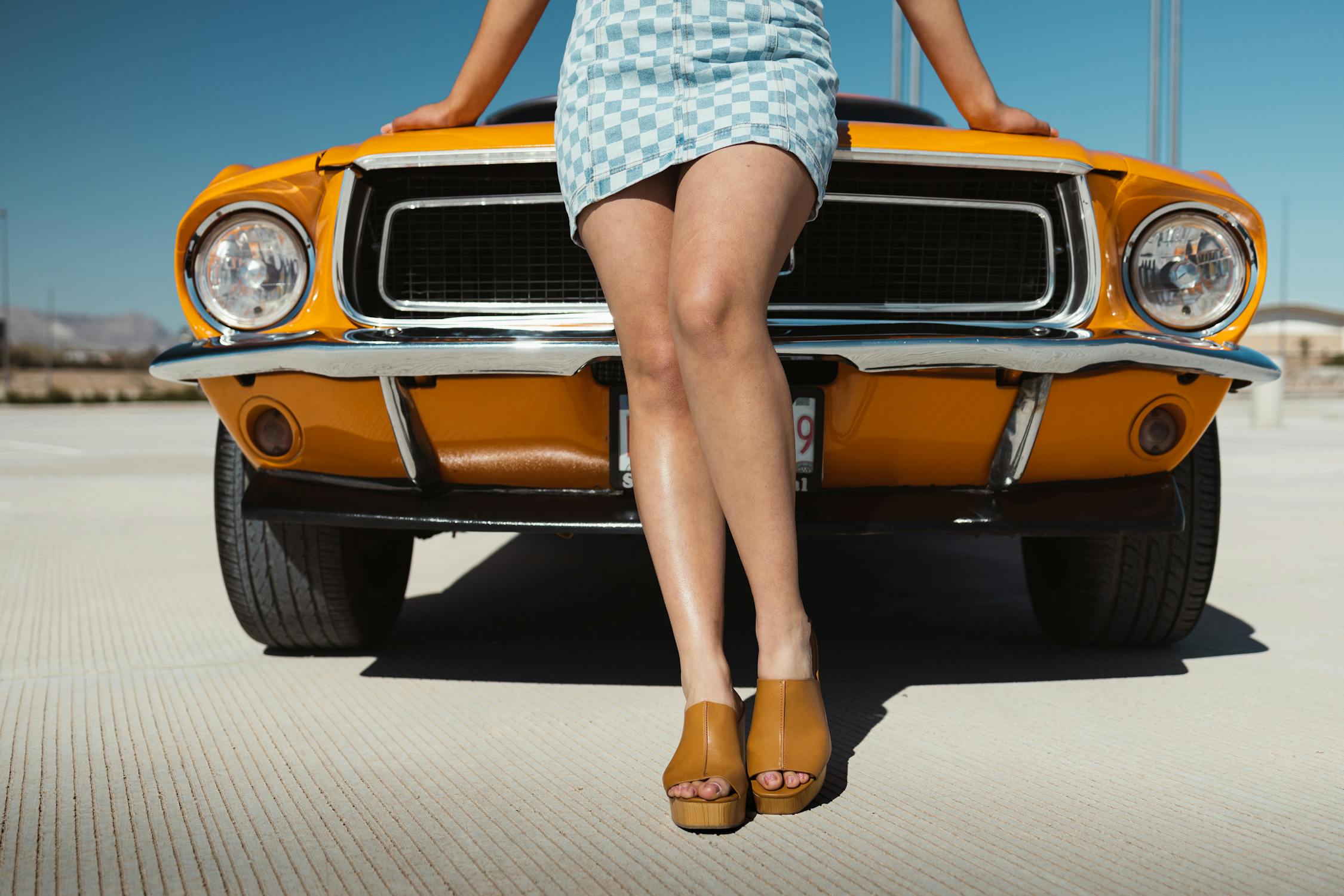 free photo of a woman in a dress and high heels standing next to a classic car