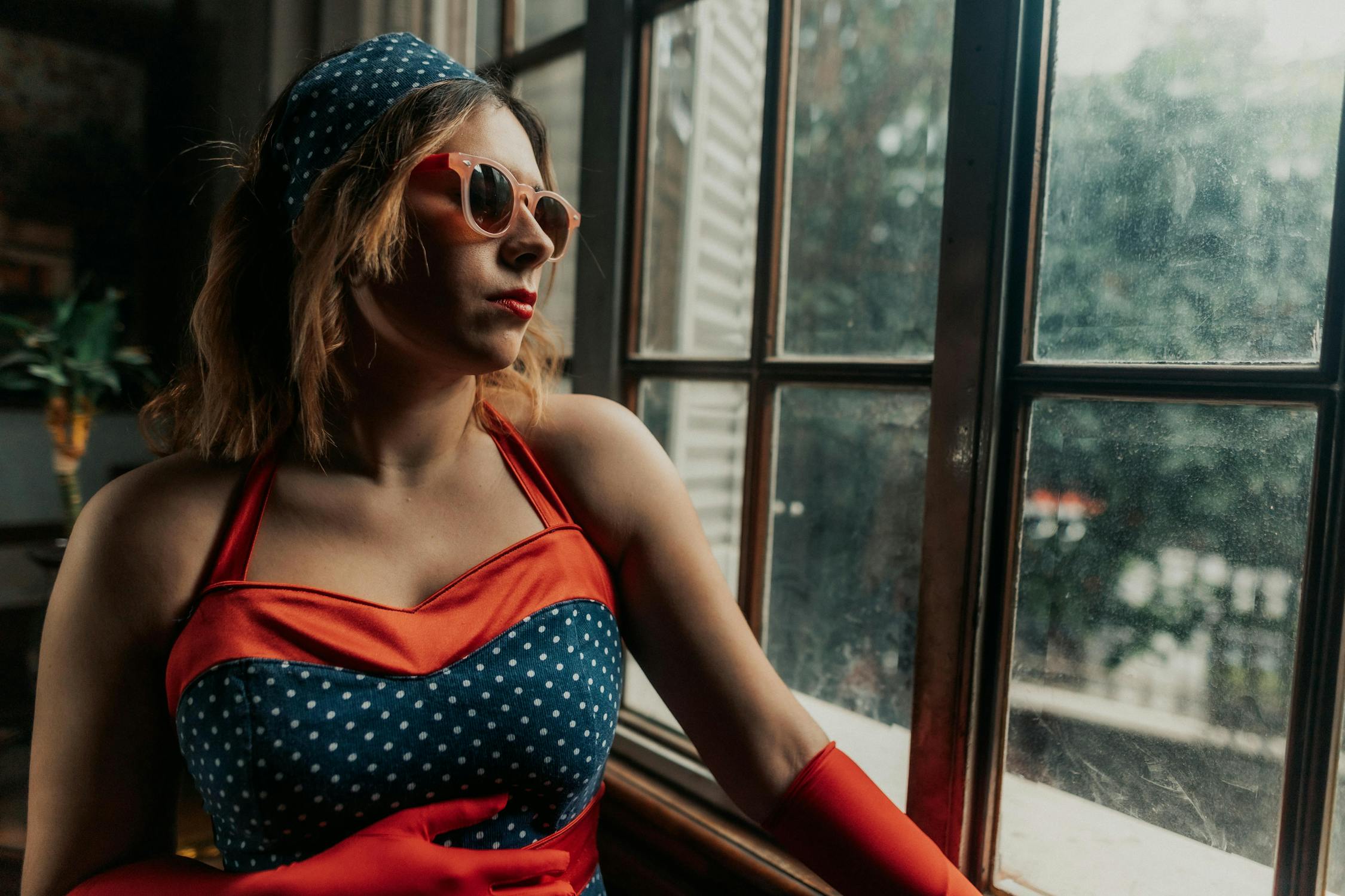 free photo of a woman in a red and blue outfit is looking out the window