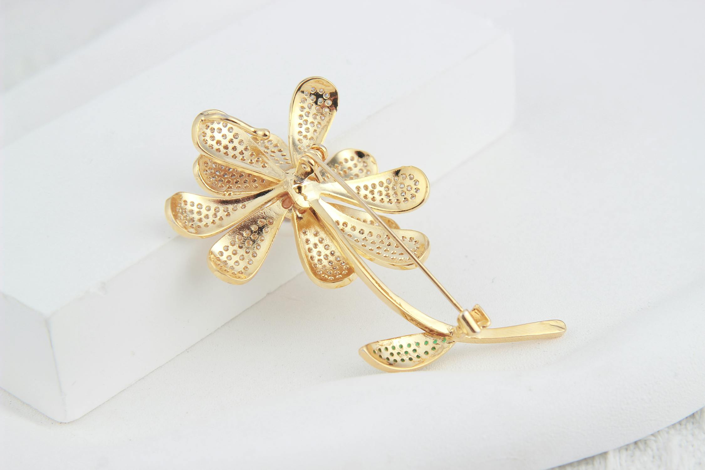 free photo of golden flower shaped brooch lying on a white background