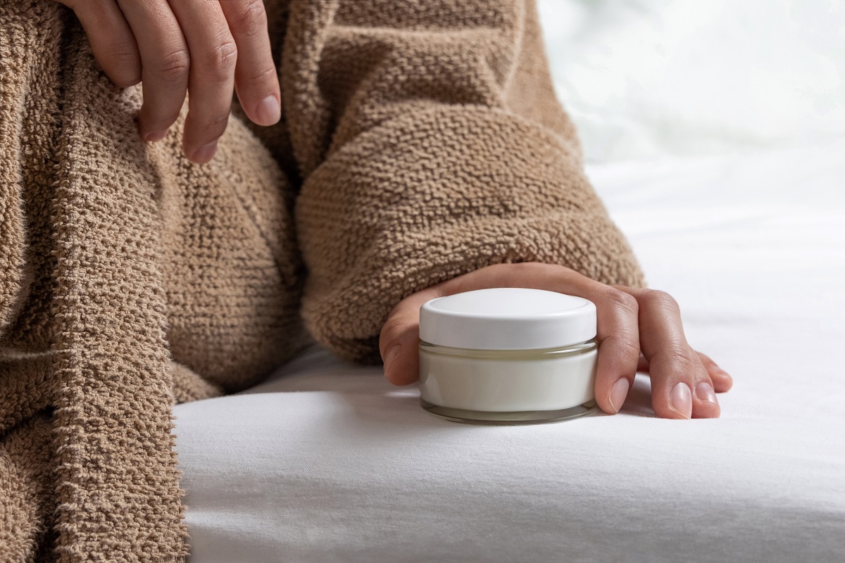 woman in brown bathrobe puts white opened cream ja 2025 03 16 05 21 34 utc